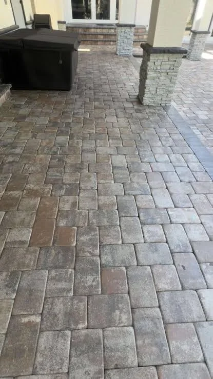 Sealed gray paver driveway with herringbone pattern and brick column detail