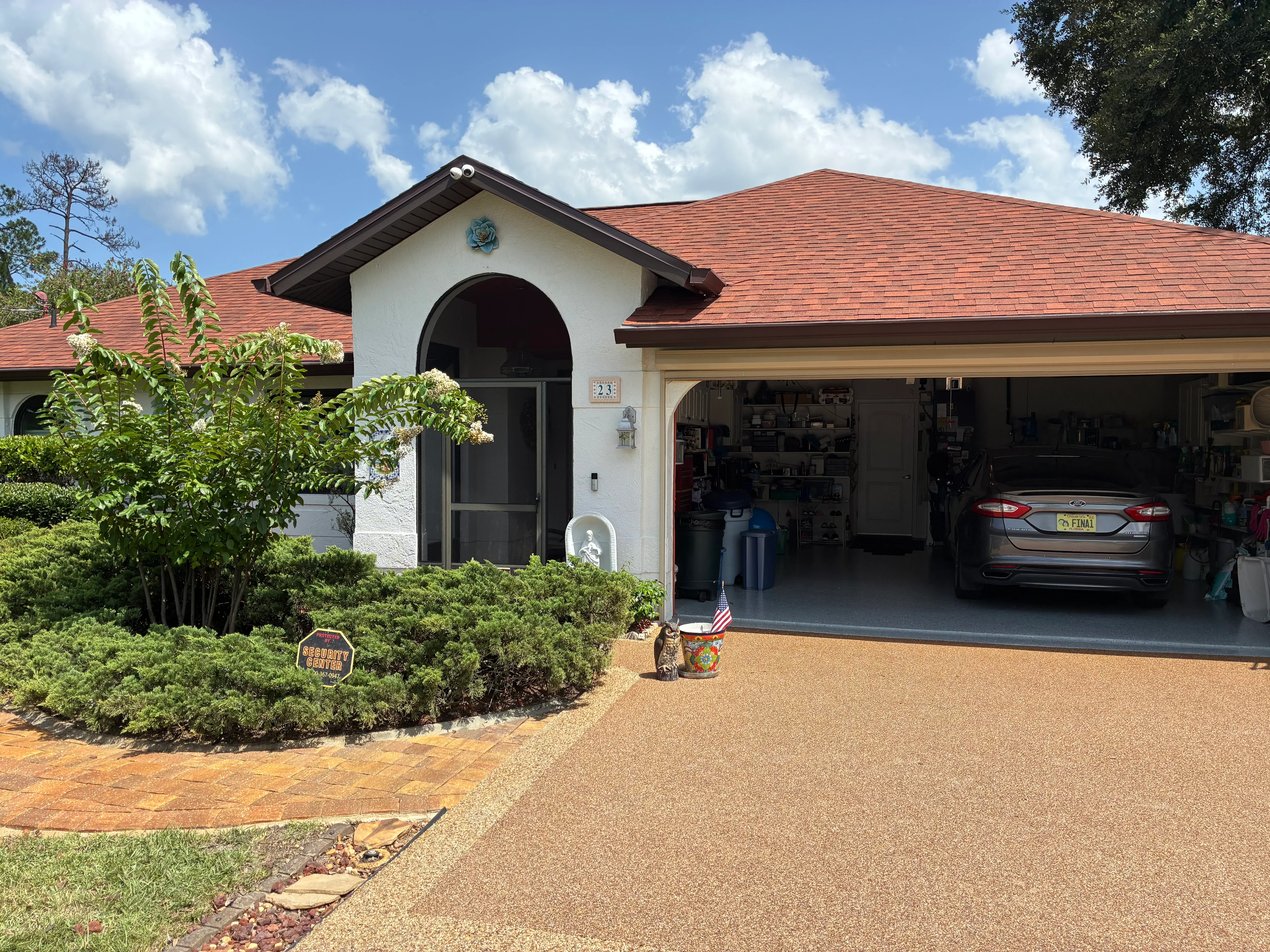 Clean residential driveway with white stucco home, terracotta roof, and manicured landscaping