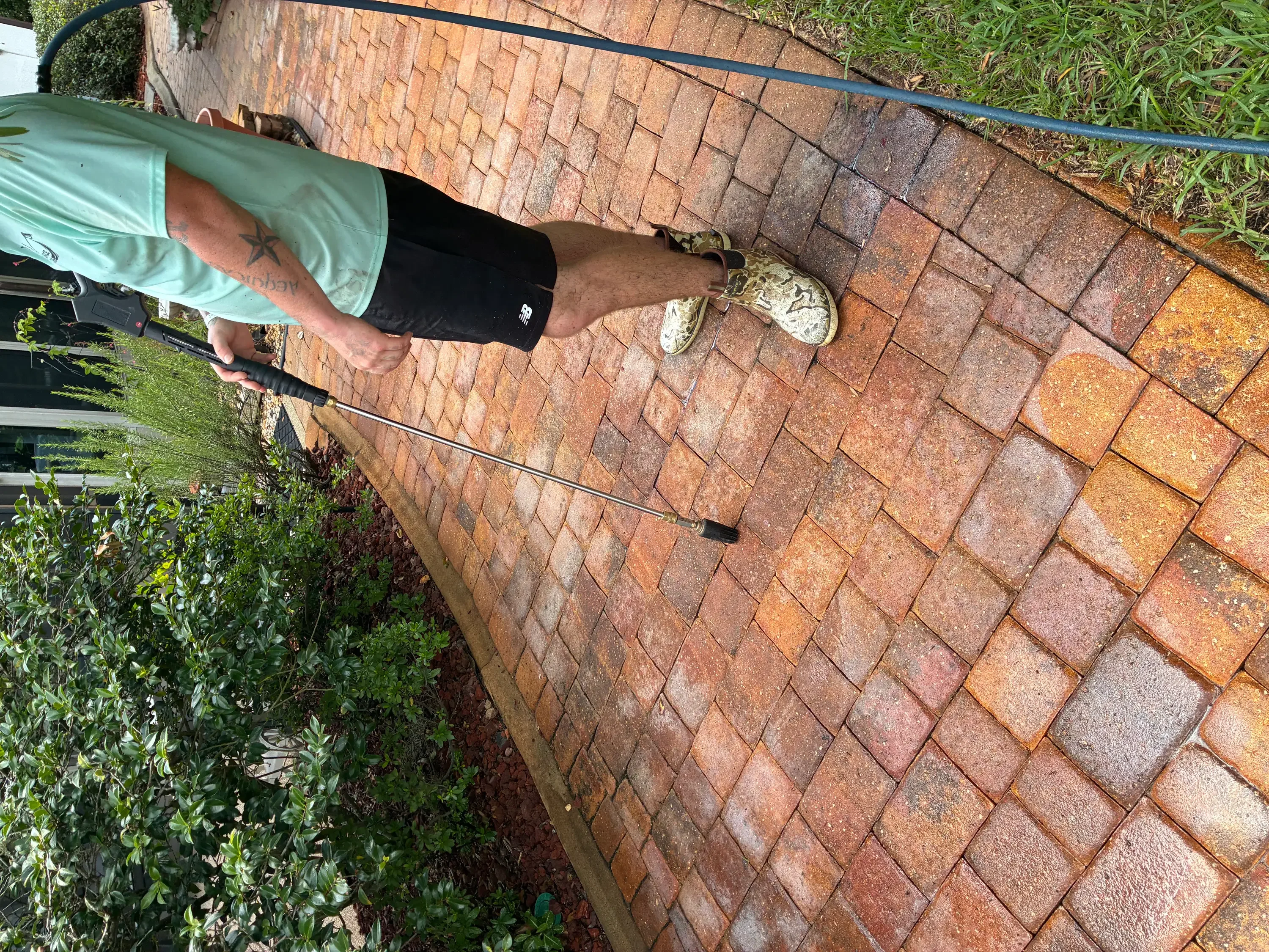 Technician pressure washing brick pavers on residential patio in Palm Coast