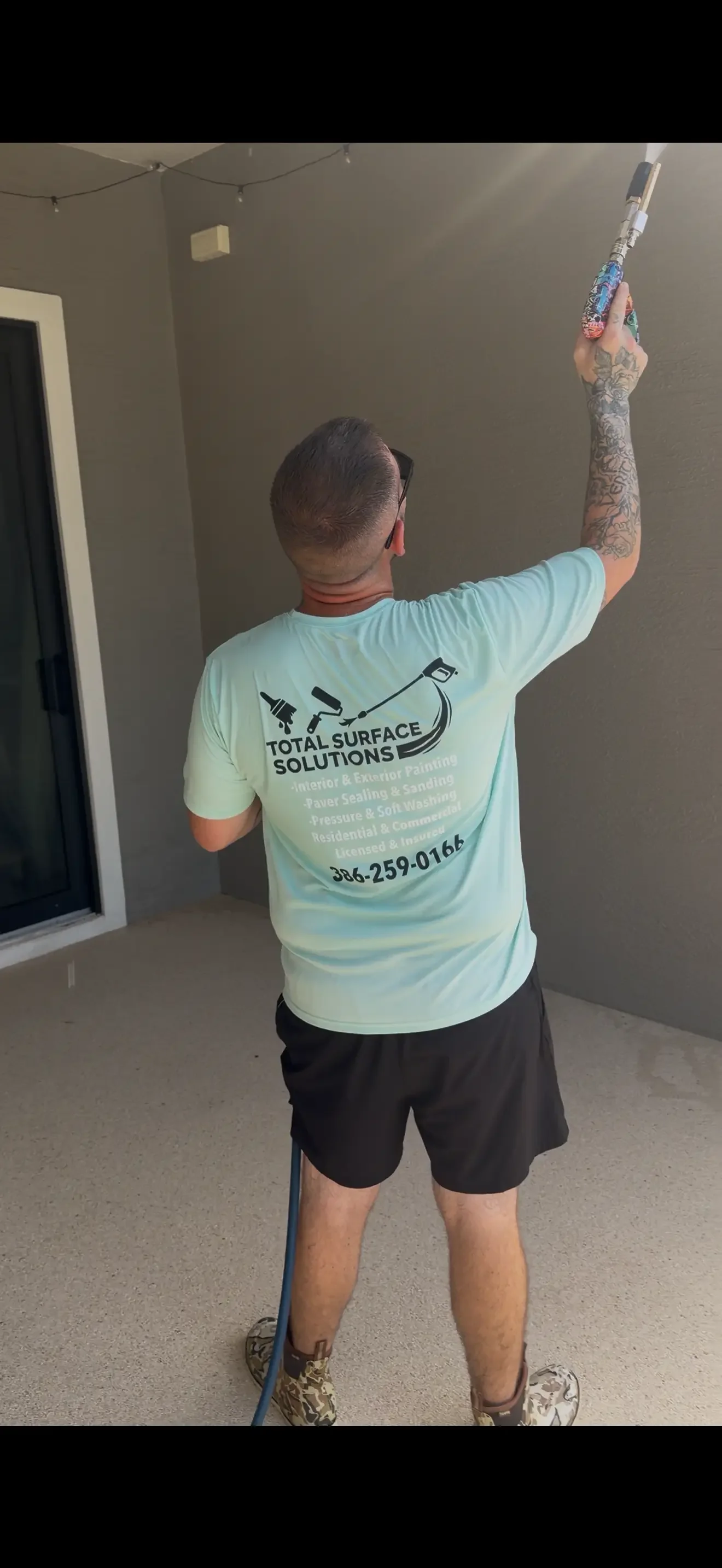 Technician pressure washing interior ceiling with specialized equipment in residential space