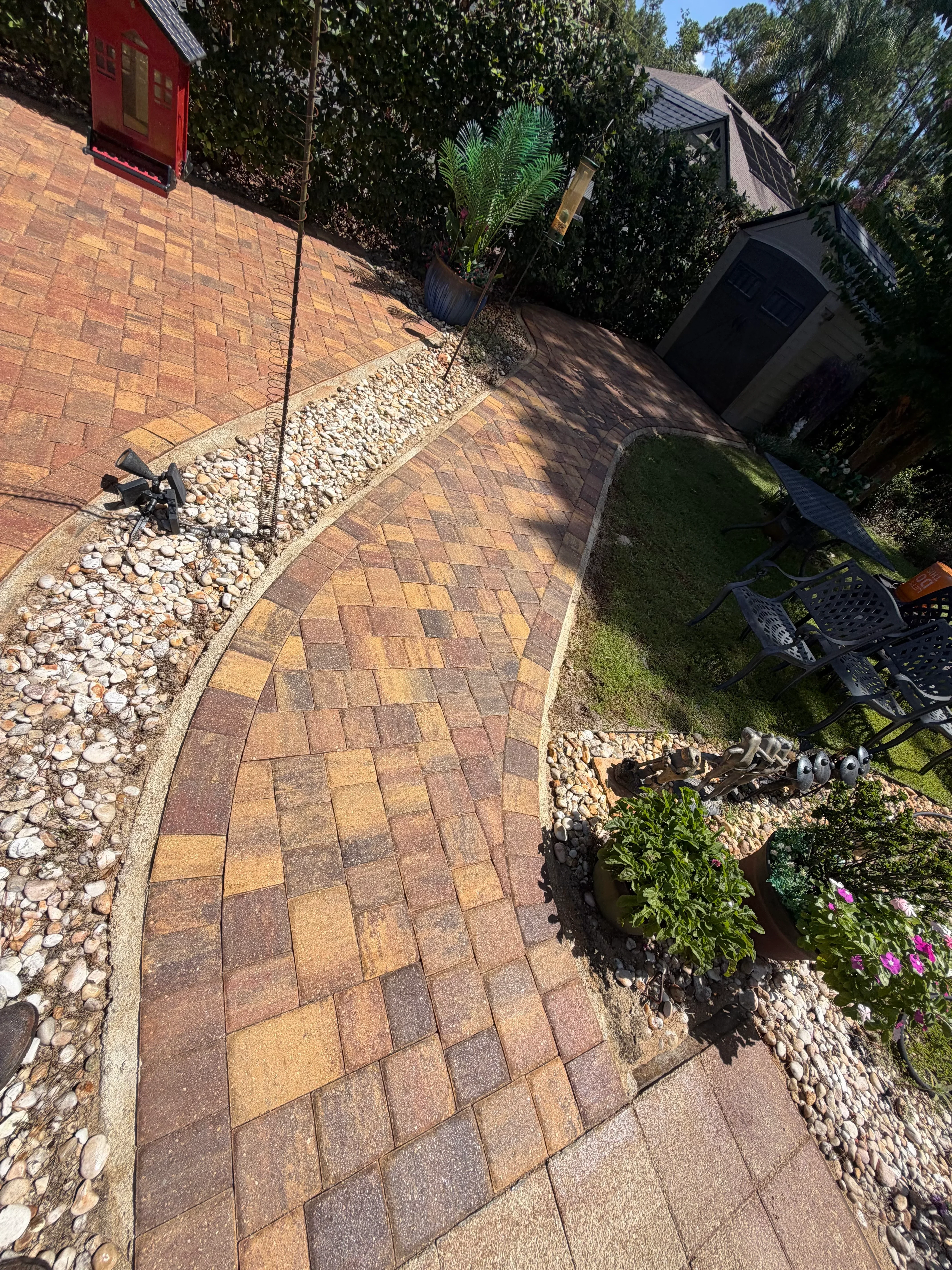 Sealed herringbone brick paver pathway with white stone borders and landscaping