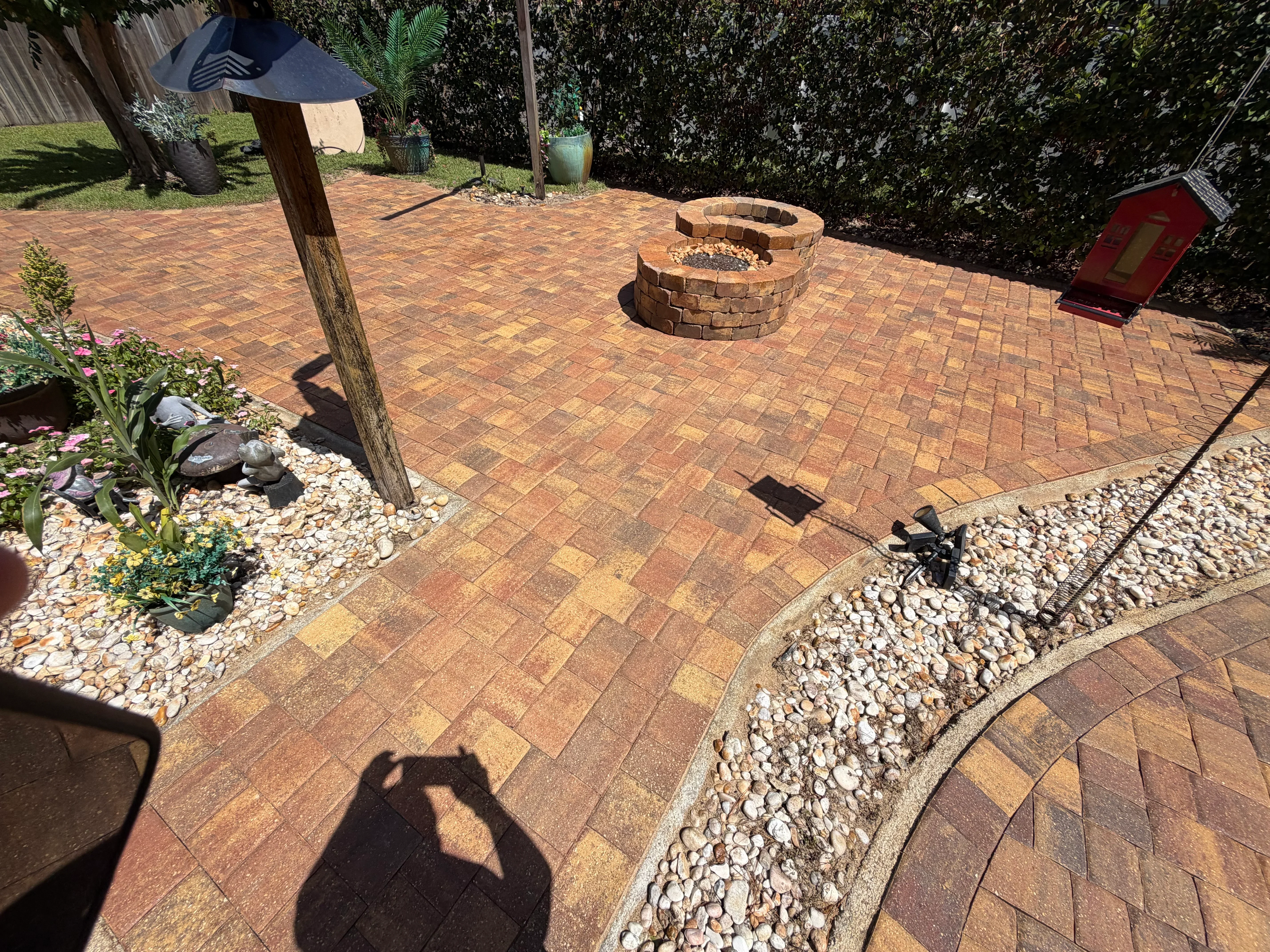 Clay brick paver patio with herringbone pattern, circular fire pit, and river rock borders